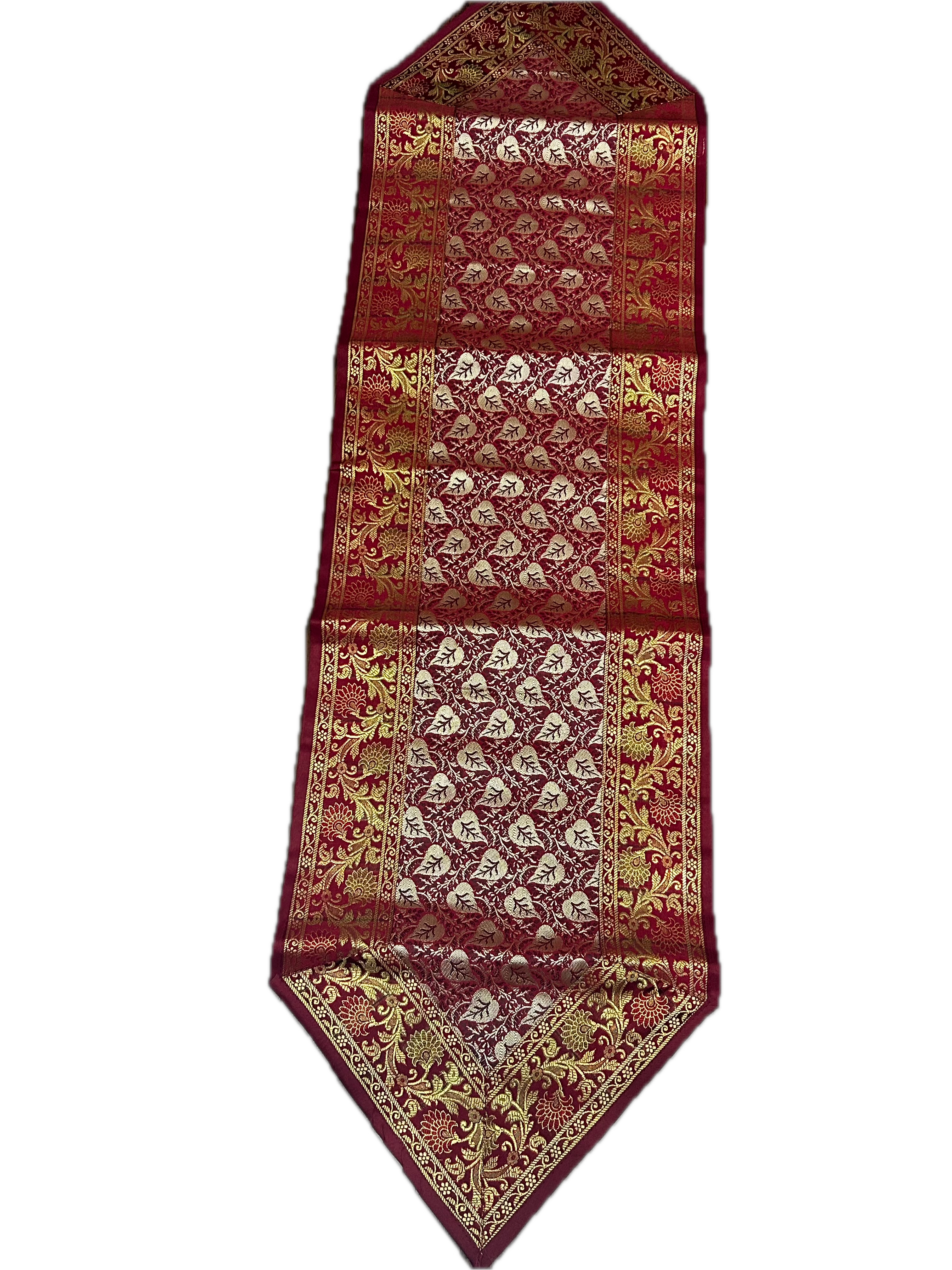 Full view of the long deep crimson table runner displaying a detailed, shimmering gold and silver traditional Indian brocade pattern.